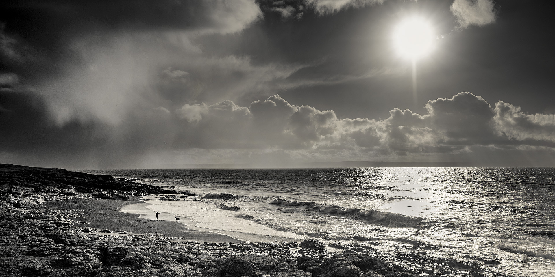 man throwing stick to dog, Brig-y-don beach, ogmore by sea, south wales, heritage coast