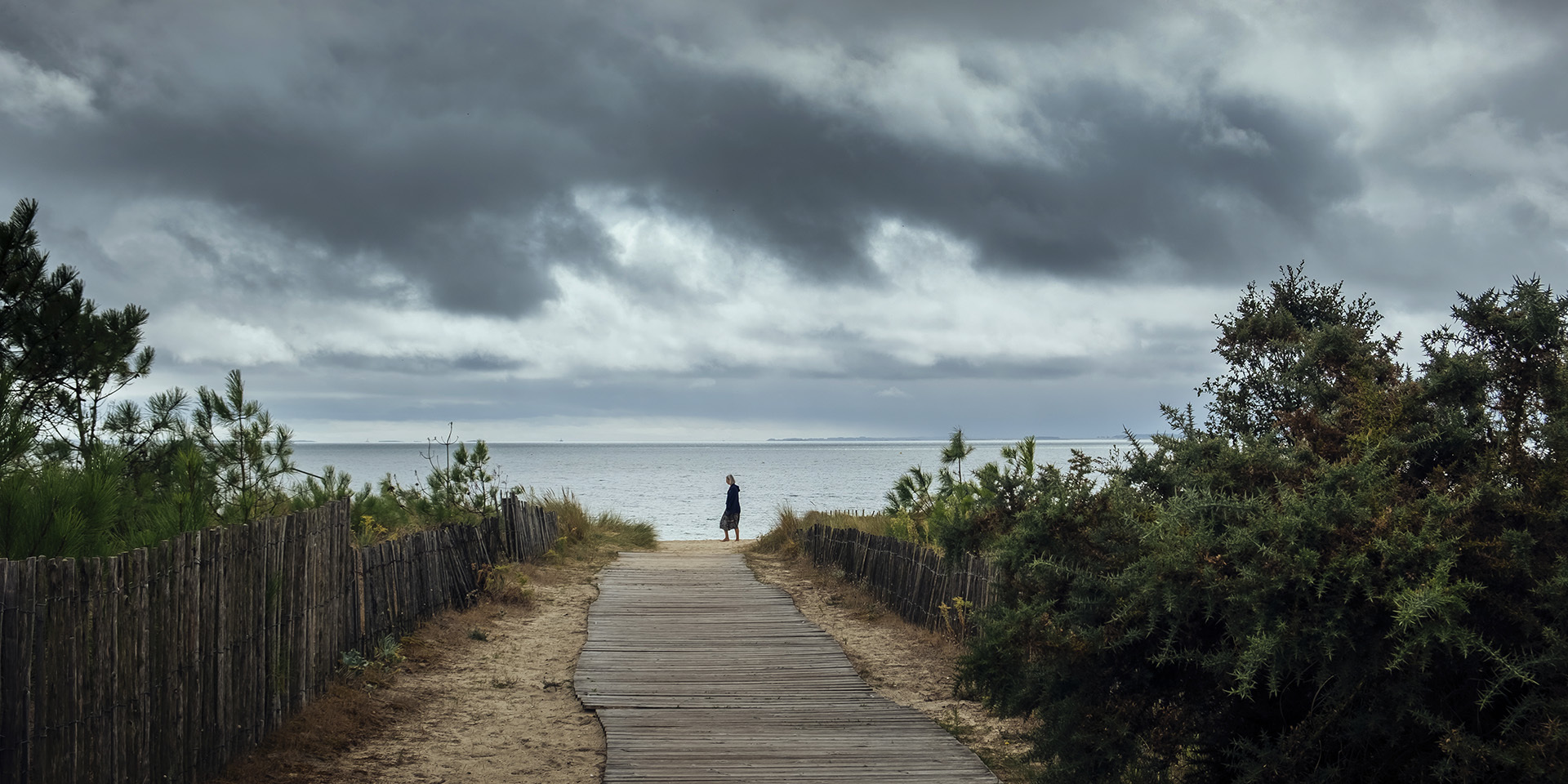 woman walking on windy  Carnac beach, Britanny France, cloudy