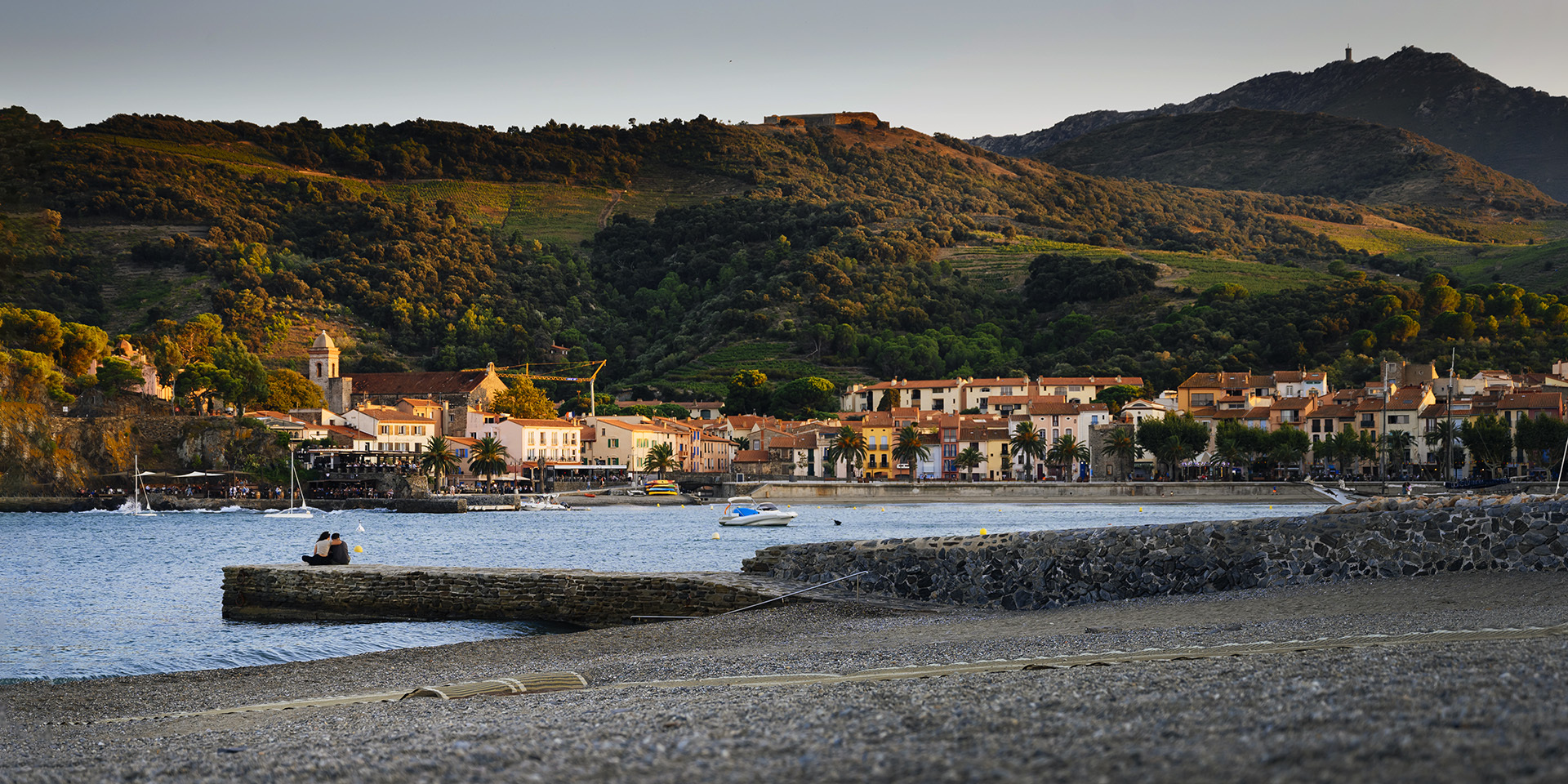 couple sitting on breakwater, Coliote harbour with evening light,, southern France